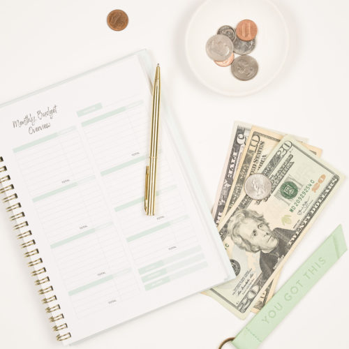 To avoid a surprise a monthly budget tracker with a pen and cash bills and coins